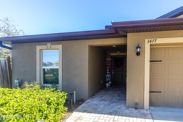 entrance to property with a garage and stucco siding