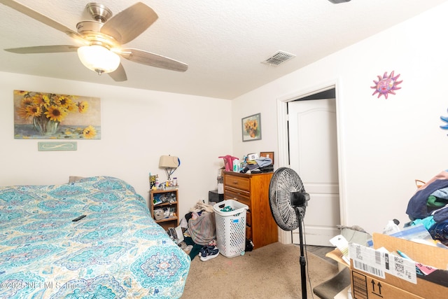 bedroom featuring carpet floors, a ceiling fan, visible vents, and a textured ceiling