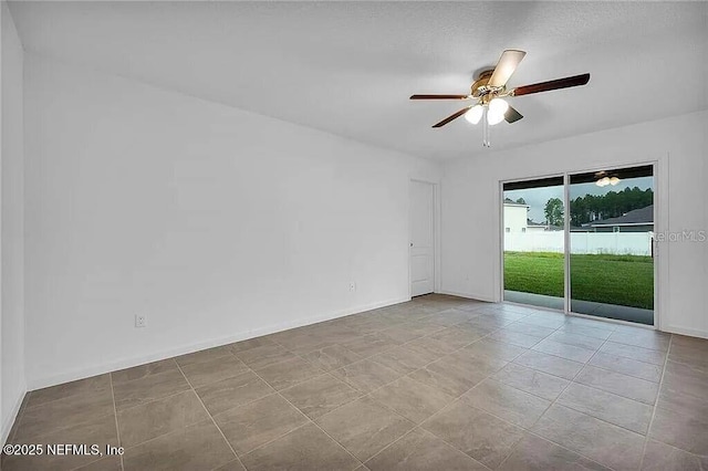 spare room featuring a ceiling fan and baseboards