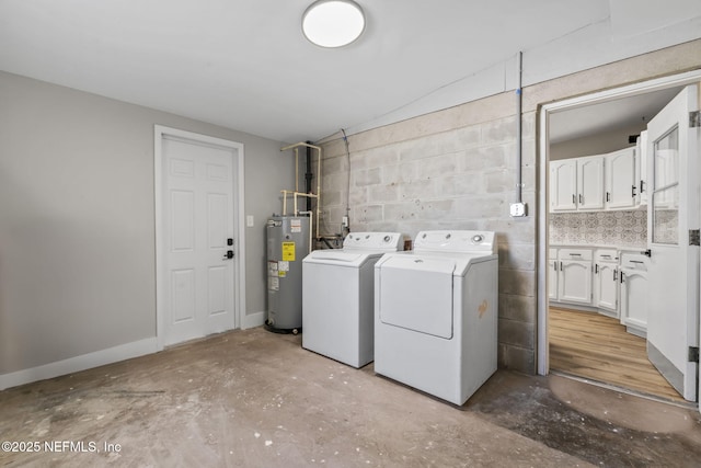 laundry area featuring concrete block wall, electric water heater, washer and dryer, laundry area, and baseboards