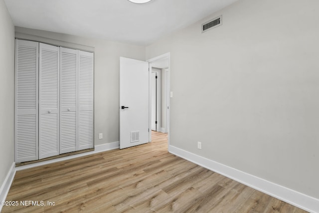 unfurnished bedroom with baseboards, visible vents, and wood finished floors