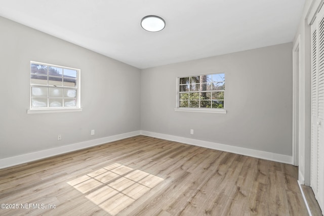 unfurnished bedroom featuring light wood-type flooring, baseboards, and a closet