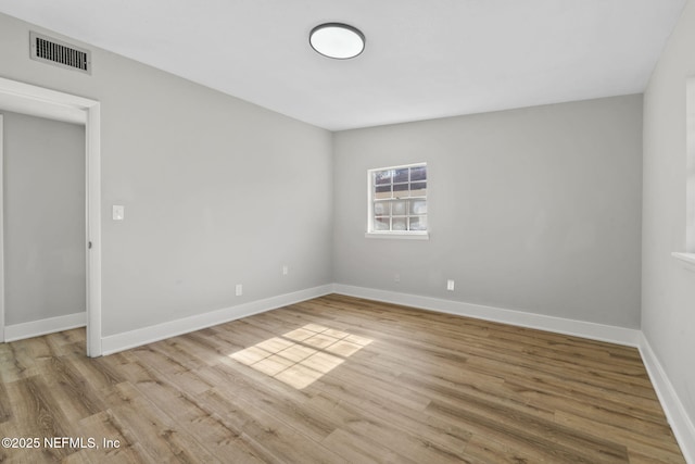 unfurnished room featuring baseboards, visible vents, and light wood finished floors