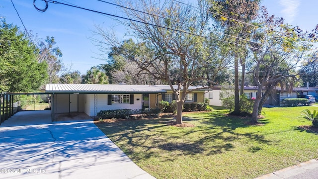 ranch-style home featuring driveway, metal roof, an attached carport, and a front yard