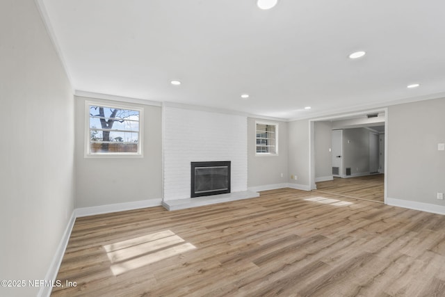 unfurnished living room featuring light wood finished floors, a fireplace, and crown molding