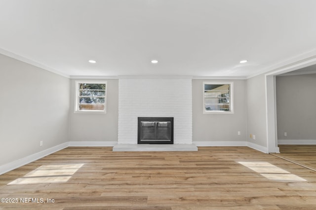 unfurnished living room featuring recessed lighting, a fireplace, baseboards, and wood finished floors