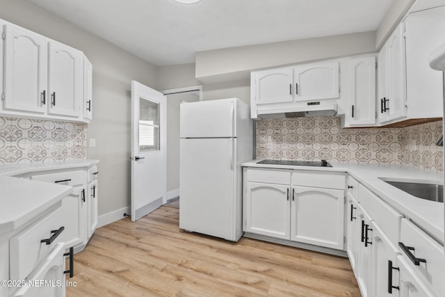 kitchen featuring light wood-style flooring, freestanding refrigerator, white cabinetry, under cabinet range hood, and black electric cooktop