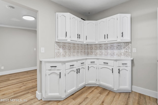 kitchen with light countertops, decorative backsplash, light wood-style floors, white cabinetry, and baseboards