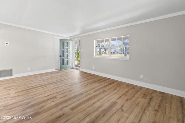 spare room featuring ornamental molding, visible vents, baseboards, and wood finished floors