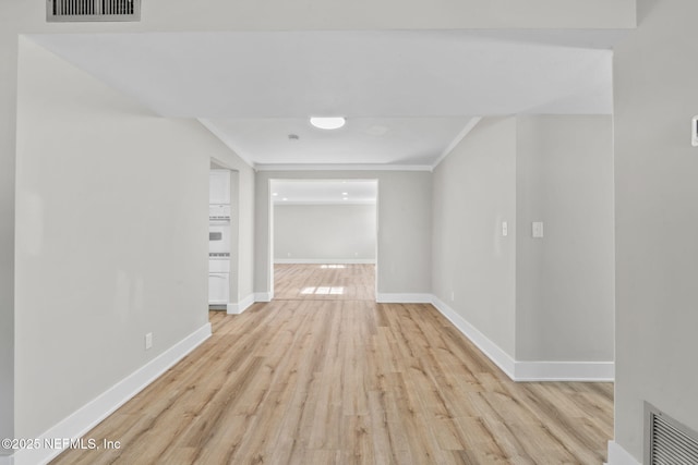 hallway with crown molding, wood finished floors, visible vents, and baseboards