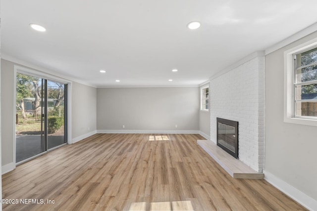 unfurnished living room with baseboards, a fireplace, light wood-style flooring, and a healthy amount of sunlight