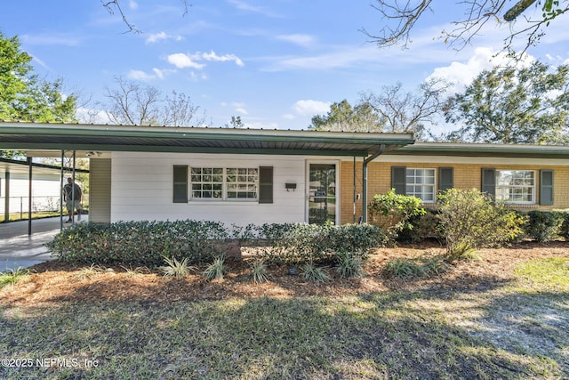 single story home featuring an attached carport, brick siding, and driveway