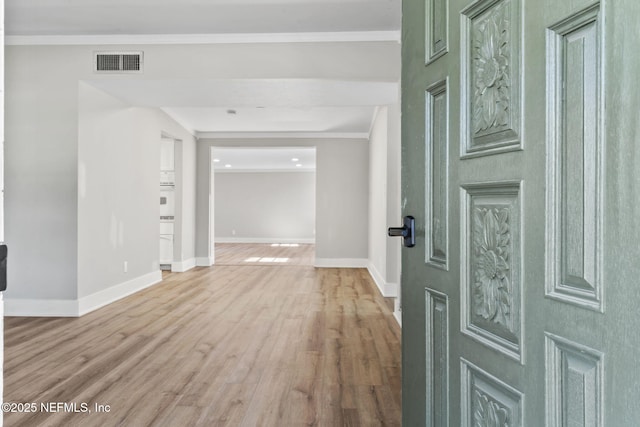 hall featuring baseboards, crown molding, visible vents, and wood finished floors