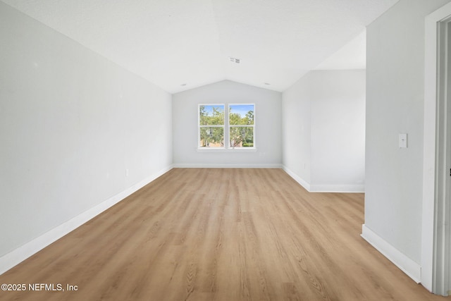 unfurnished room with light wood-style floors, visible vents, vaulted ceiling, and baseboards