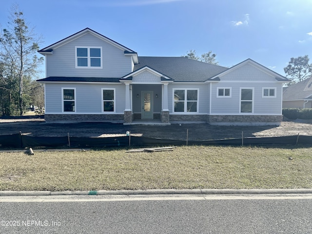 view of front of home featuring stone siding and a front lawn