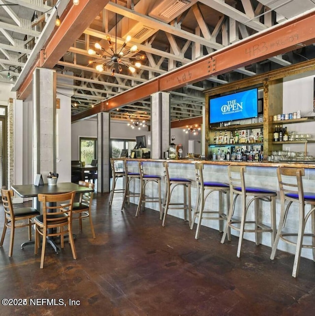dining room with finished concrete flooring, a chandelier, and a community bar