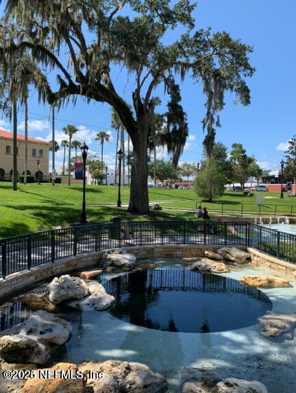 view of community with fence, a yard, and a pool