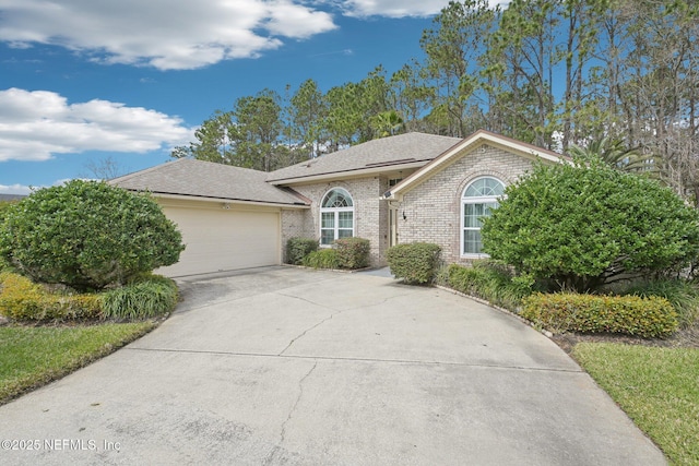 single story home featuring a garage, concrete driveway, brick siding, and roof with shingles