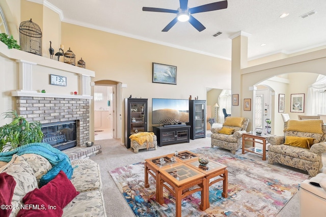 living area featuring arched walkways, carpet floors, a fireplace, visible vents, and crown molding