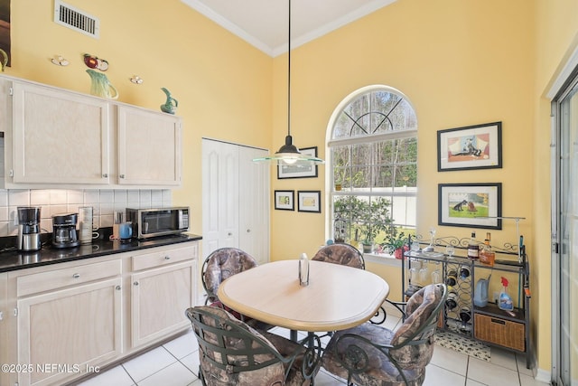 dining room featuring light tile patterned floors, a ceiling fan, visible vents, and crown molding