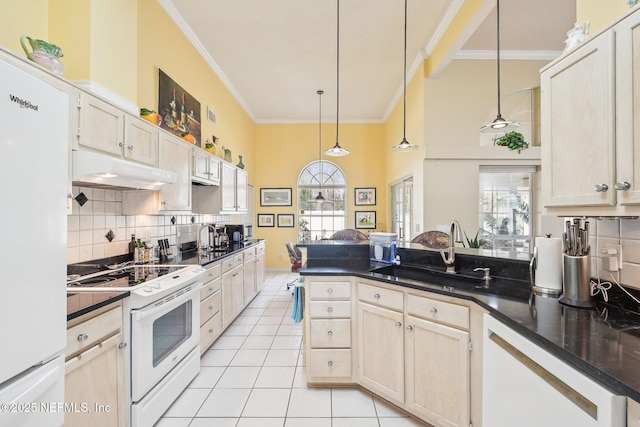 kitchen featuring dark countertops, a sink, a peninsula, white appliances, and under cabinet range hood