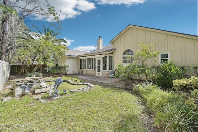 rear view of property featuring a patio, fence, a sunroom, a yard, and a chimney