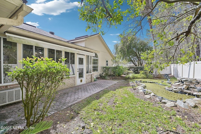 view of yard with a patio, fence, and a sunroom