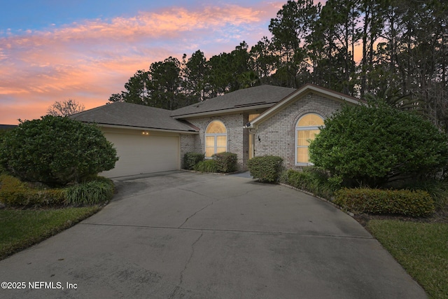 single story home with a garage, brick siding, and driveway