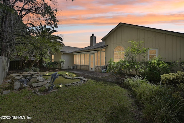 back of property with a chimney, a lawn, a patio area, and fence