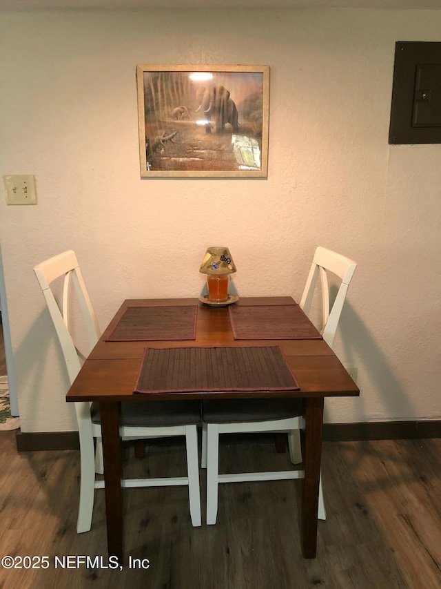 dining room with electric panel, baseboards, and wood finished floors