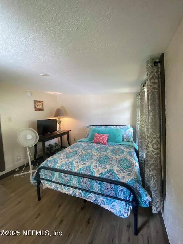 bedroom featuring a textured ceiling, baseboards, and wood finished floors