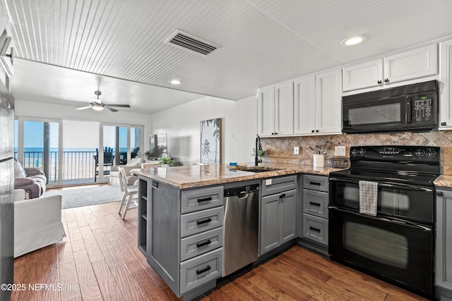 kitchen featuring visible vents, black appliances, gray cabinetry, a sink, and a peninsula