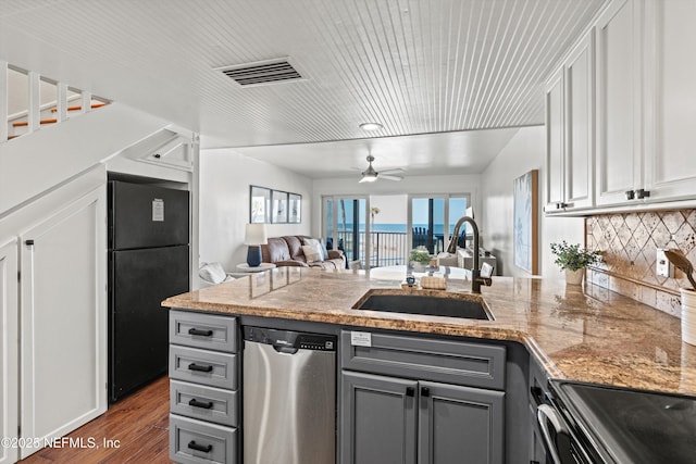 kitchen with visible vents, a peninsula, freestanding refrigerator, a sink, and dishwasher