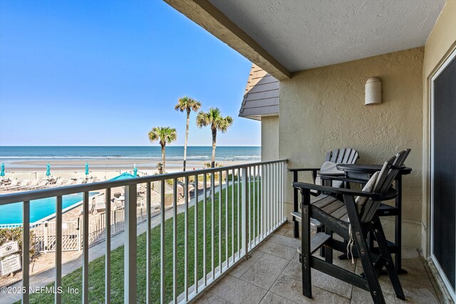 balcony featuring a view of the beach and a water view