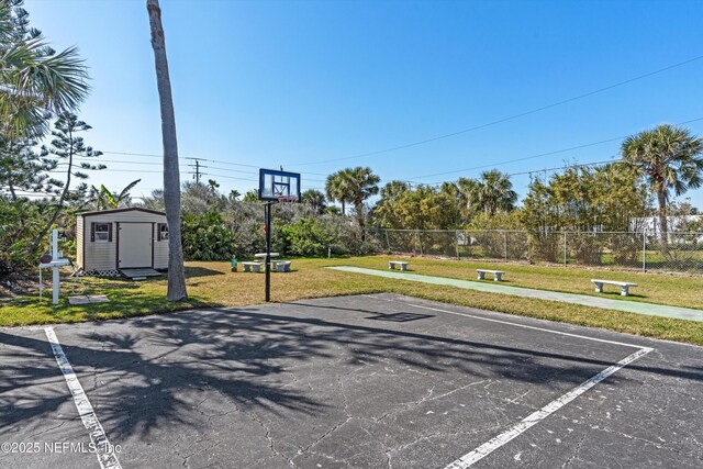 view of sport court with a lawn, fence, and a shed