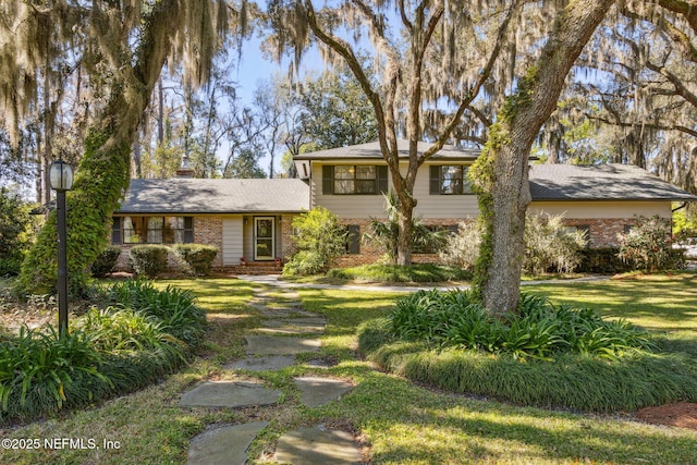 view of front of home featuring brick siding, a chimney, and a front lawn