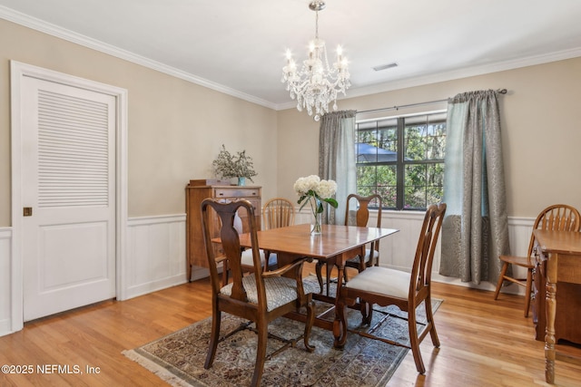 dining room featuring visible vents, a notable chandelier, a wainscoted wall, and light wood finished floors