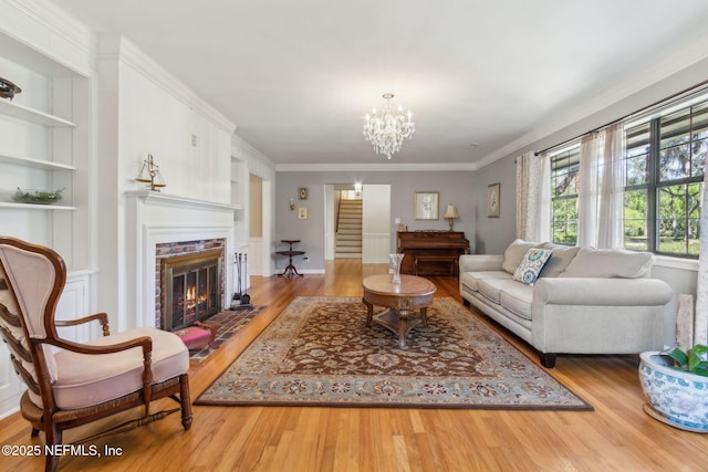 living area with a glass covered fireplace, built in shelves, and wood finished floors