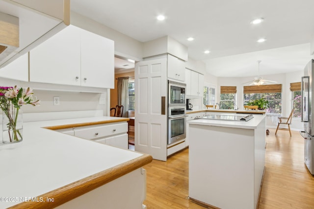 kitchen featuring light wood finished floors, light countertops, recessed lighting, a peninsula, and stainless steel appliances