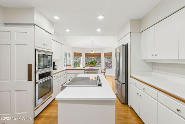 kitchen featuring white cabinets, light wood-type flooring, a kitchen island, and stainless steel appliances