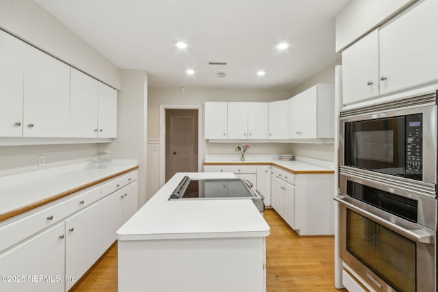 kitchen with a center island, recessed lighting, light wood-style floors, appliances with stainless steel finishes, and white cabinets