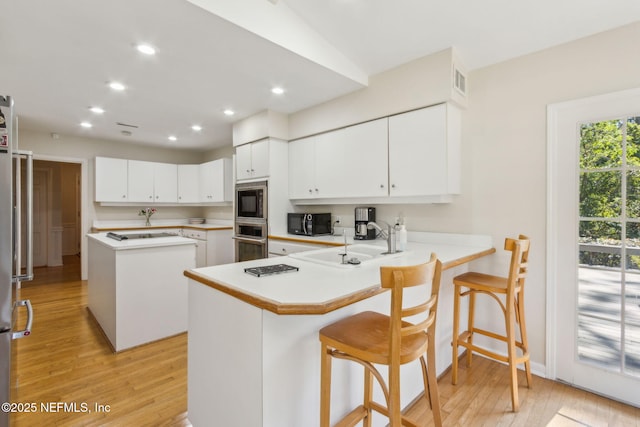 kitchen with appliances with stainless steel finishes, light countertops, light wood-style floors, and a sink