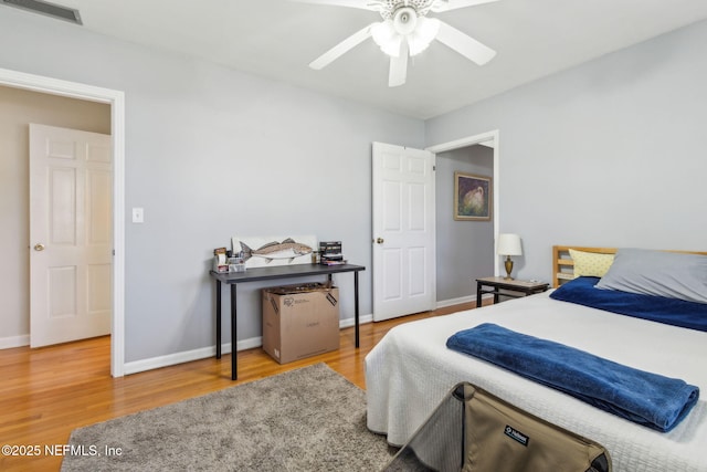 bedroom featuring visible vents, ceiling fan, baseboards, and wood finished floors