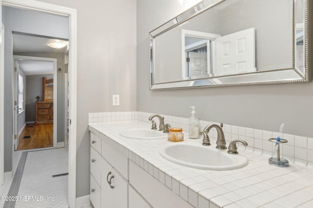 bathroom featuring double vanity, baseboards, and a sink