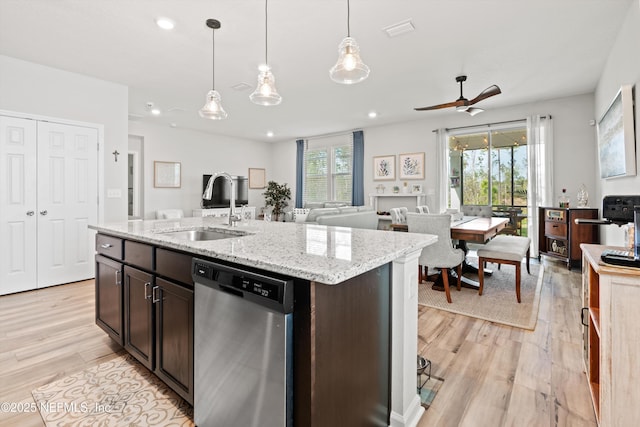 kitchen featuring a sink, light wood finished floors, open floor plan, and stainless steel dishwasher