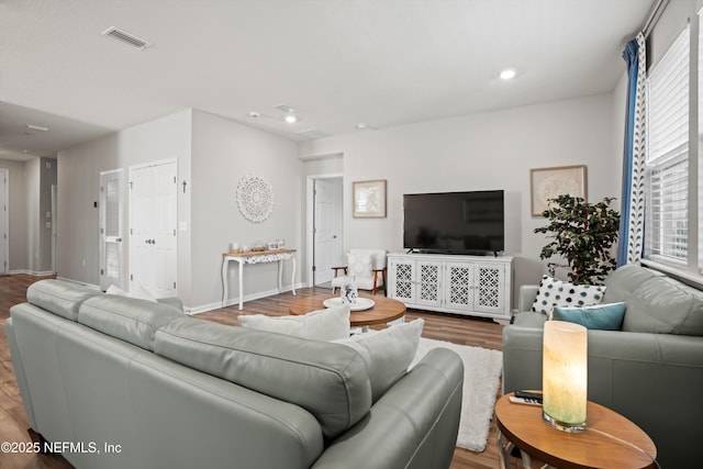 living room featuring baseboards, visible vents, wood finished floors, and recessed lighting