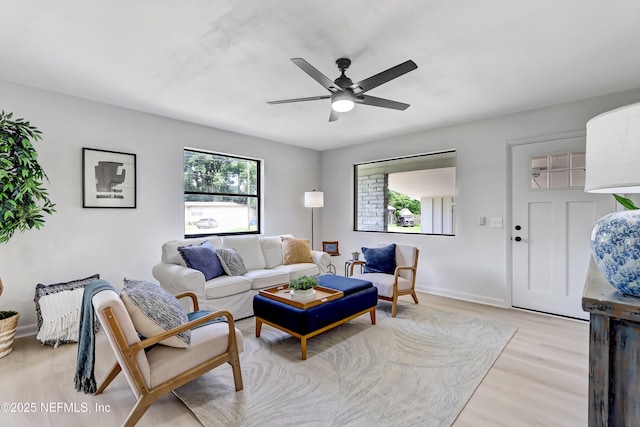 living area with light wood-style flooring, baseboards, and a ceiling fan