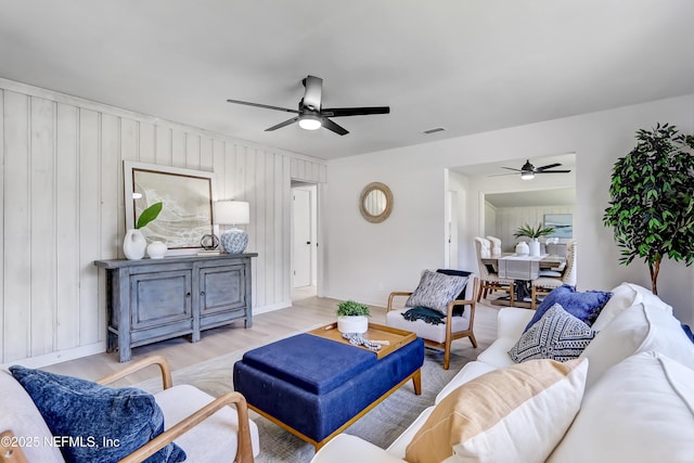 living area with baseboards, wood finished floors, visible vents, and a ceiling fan