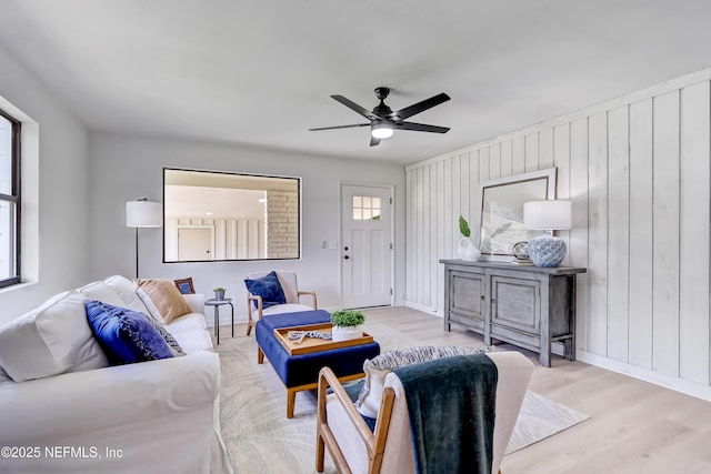 living area featuring a ceiling fan, baseboards, and wood finished floors