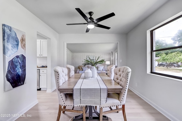 dining area featuring light wood finished floors, baseboards, and a ceiling fan